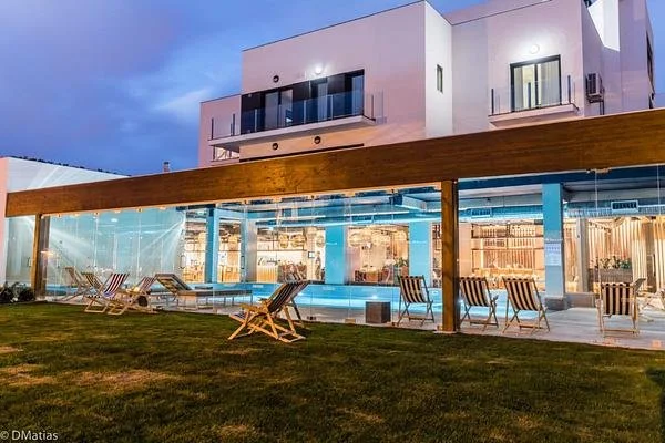 You and the Sea, a modern coastal retreat in Ericeira with large windows, a wooden pergola, outdoor seating area with deck chairs, and a glass-enclosed pool area..