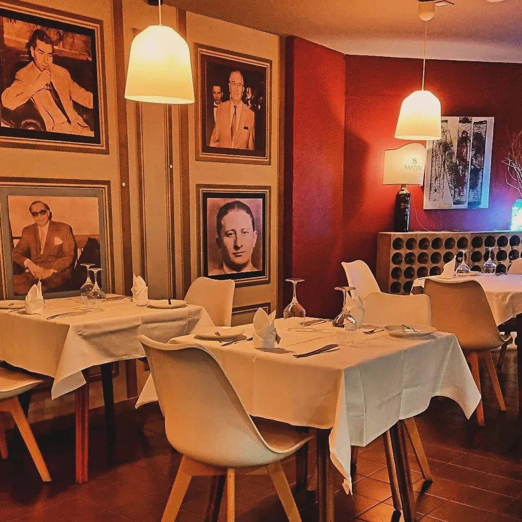 Charming table setting at Piazza di Estoril, featuring crisp white tablecloths, vibrant, red-painted walls, creating a cozy and inviting atmosphere for enjoying delicious Italian and Portuguese dishes.