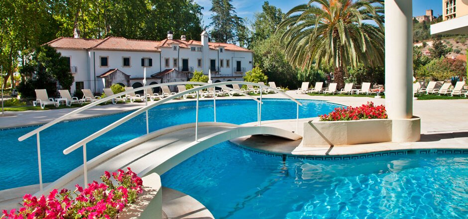 Hotel dos Templários, Tomar: Outdoor Swimming Pool with White Bridge, Lounge Chairs, Garden, and Large White Guesthouse
