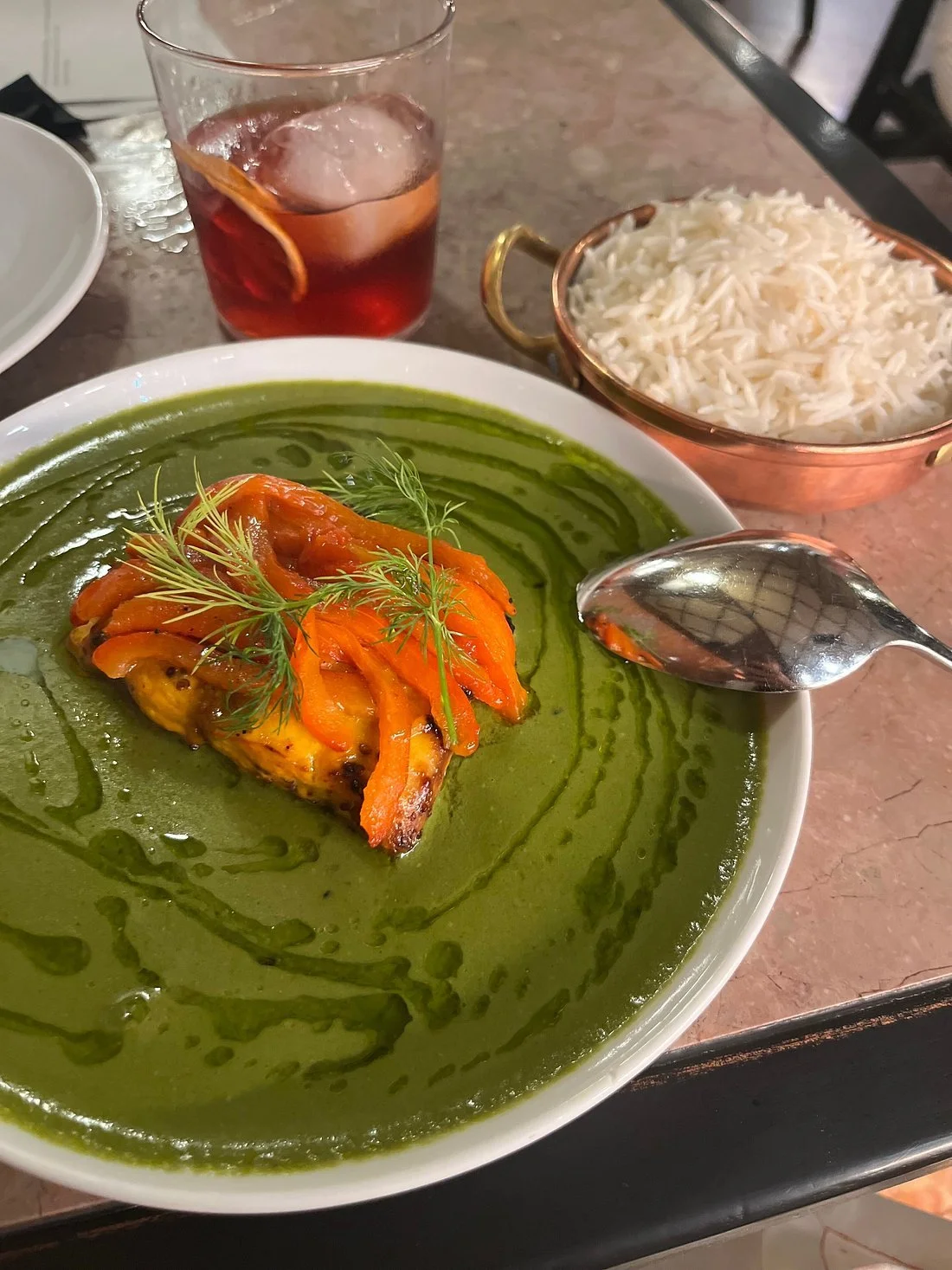 Indian green curry dish with roasted vegetables, accompanied by white rice and a glass of Sangria at Gunpowder restaurant.