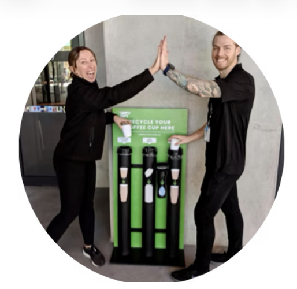 Two people standing with a simply cups collection unit and giving each other a high five