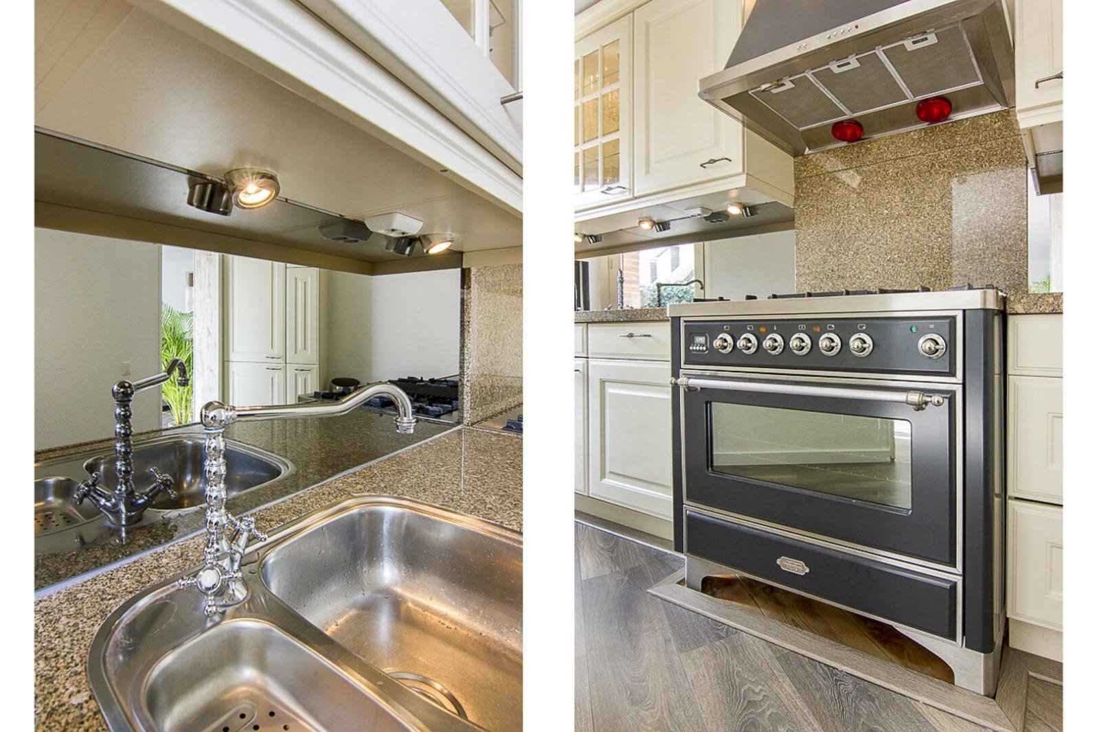 Keuken met dubbele sink, granieten werkbladen, kastjes en een oven.