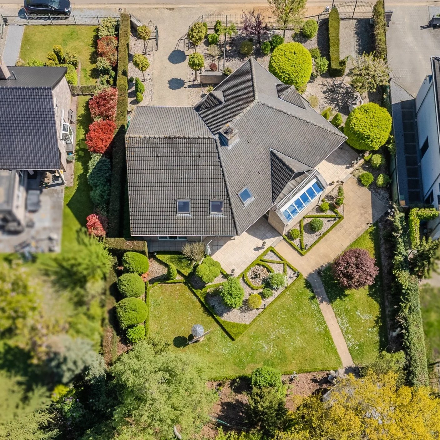 Professionele dronefoto van een vrijstaande villa met tuin en omgeving, vastgelegd vanuit de lucht.