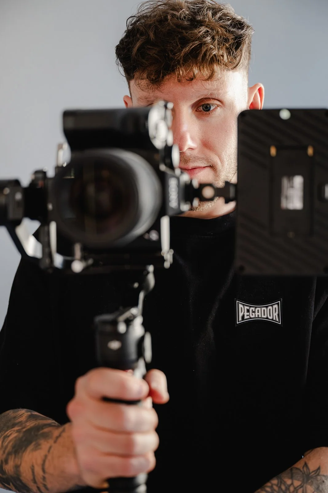 Studio Businessfotografie für Selbstständige – Porträt für Website und Social Media. Junger Mann blickt durch eine Kamera auf ein Aufnahmegerät.