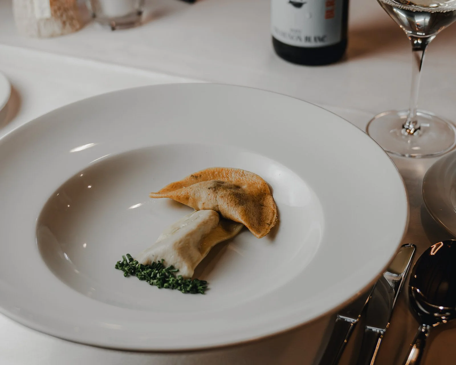 Ein weißer Teller mit zwei Tortellini, one mit Hackfleischfüllung und der andere mit Käse, garniert mit gehackten Schnittlauch. Restaurantfotografie Landgasthof Lamm in Ebnat.