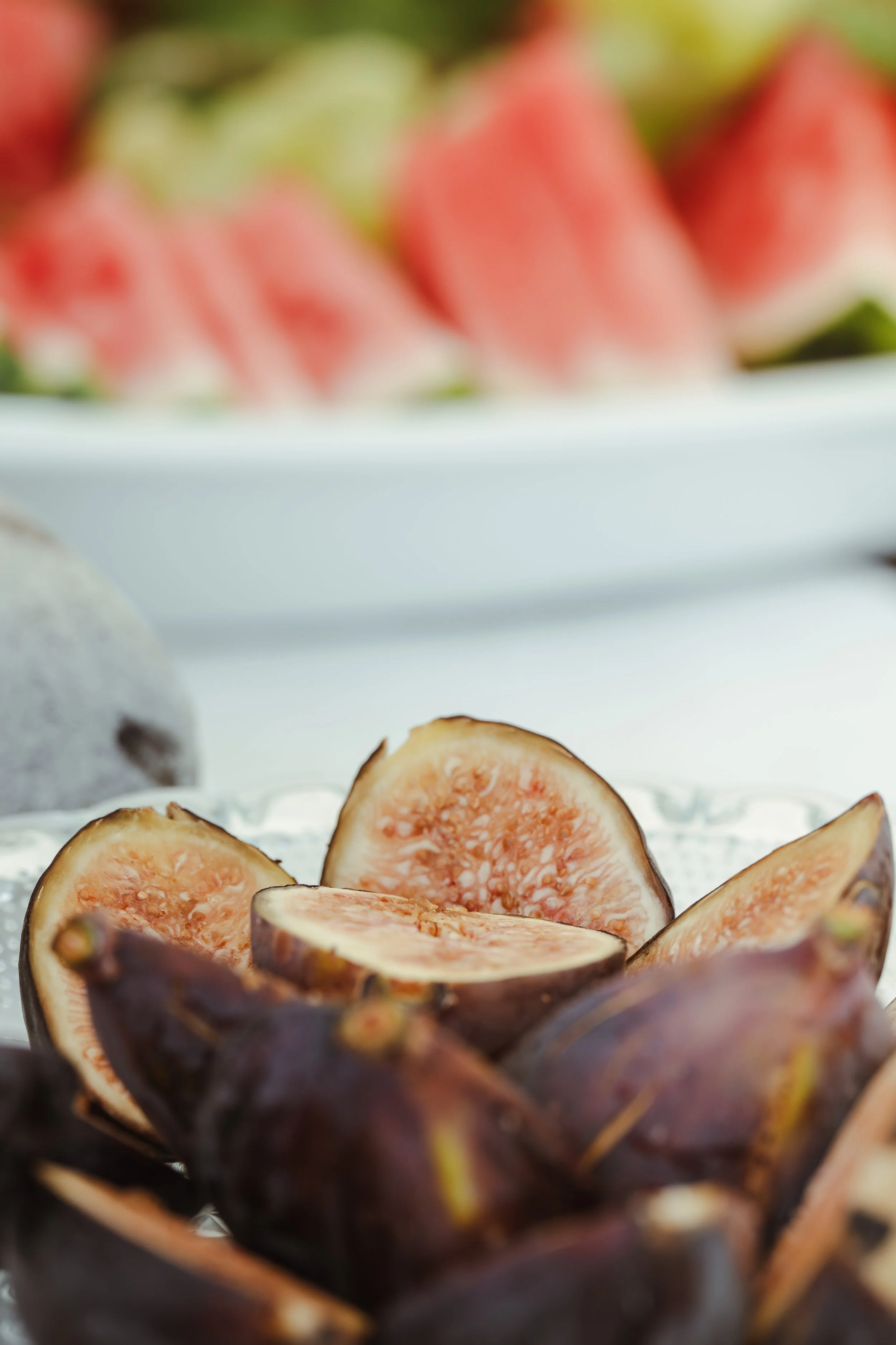 Getrocknete Feigen auf einer silbernen Platte, unscharfer Obstteller im Hintergrund.