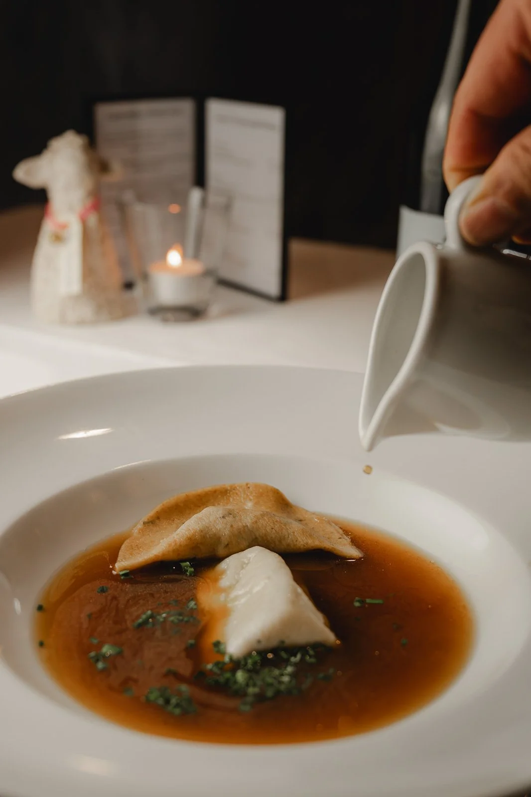 Fischknödel in Brühe mit frischen Kräutern, makroaufnahme, Restauranttisch, dunkler Hintergrund. Restaurantfotografie Landgasthof Lamm in Ebnat.