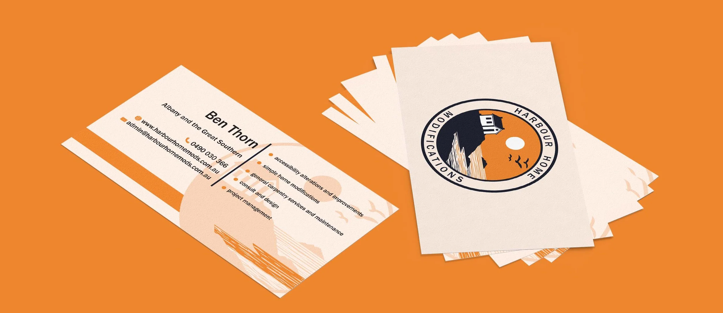 Business cards for Harbour Home Modifications on an orange background. One card displays contact details and services such as accessibility alterations and project management, while the other features the company logo with a coastal design.