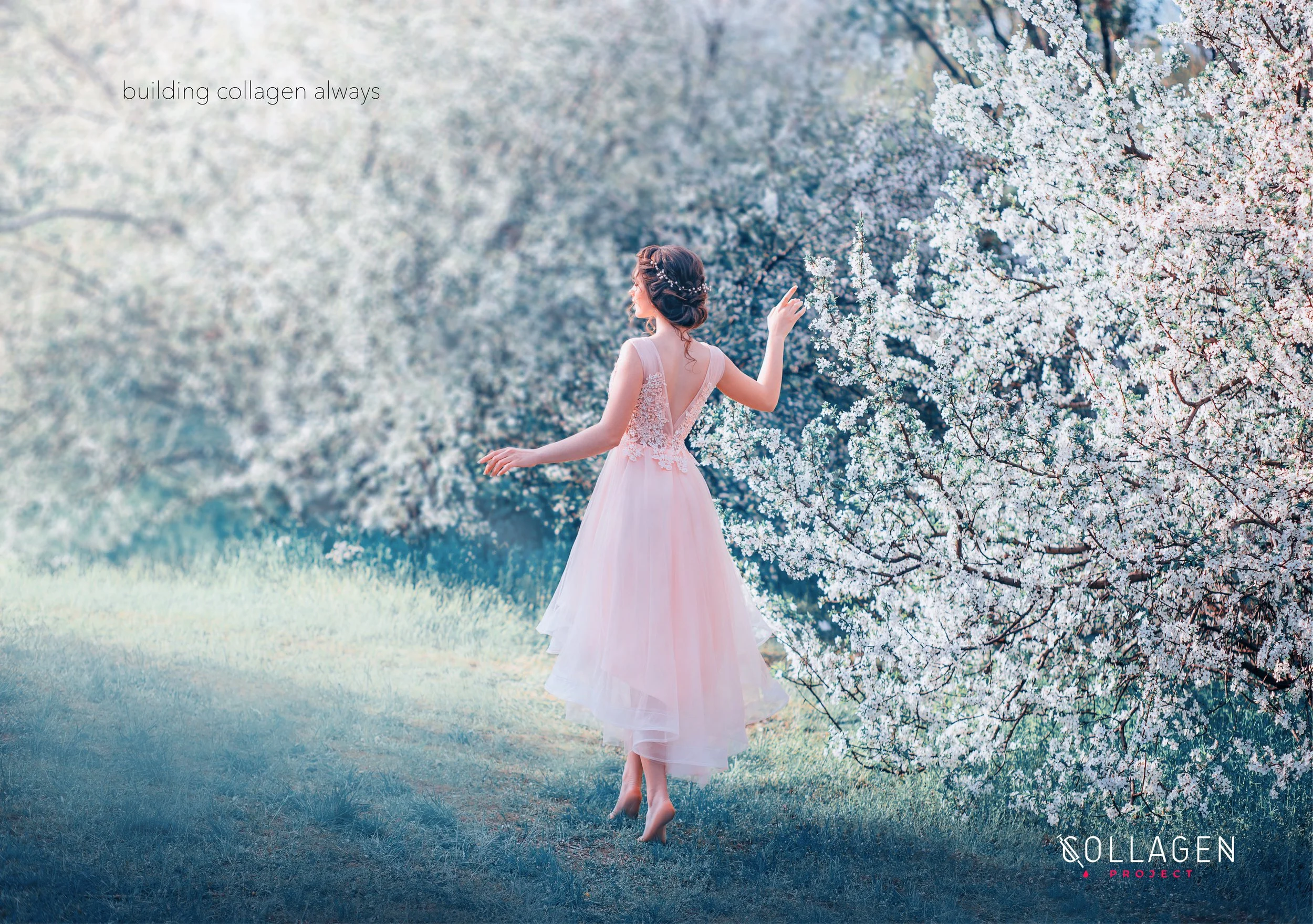 A woman in a pink dress standing on grass in front of blossoming white flowers.