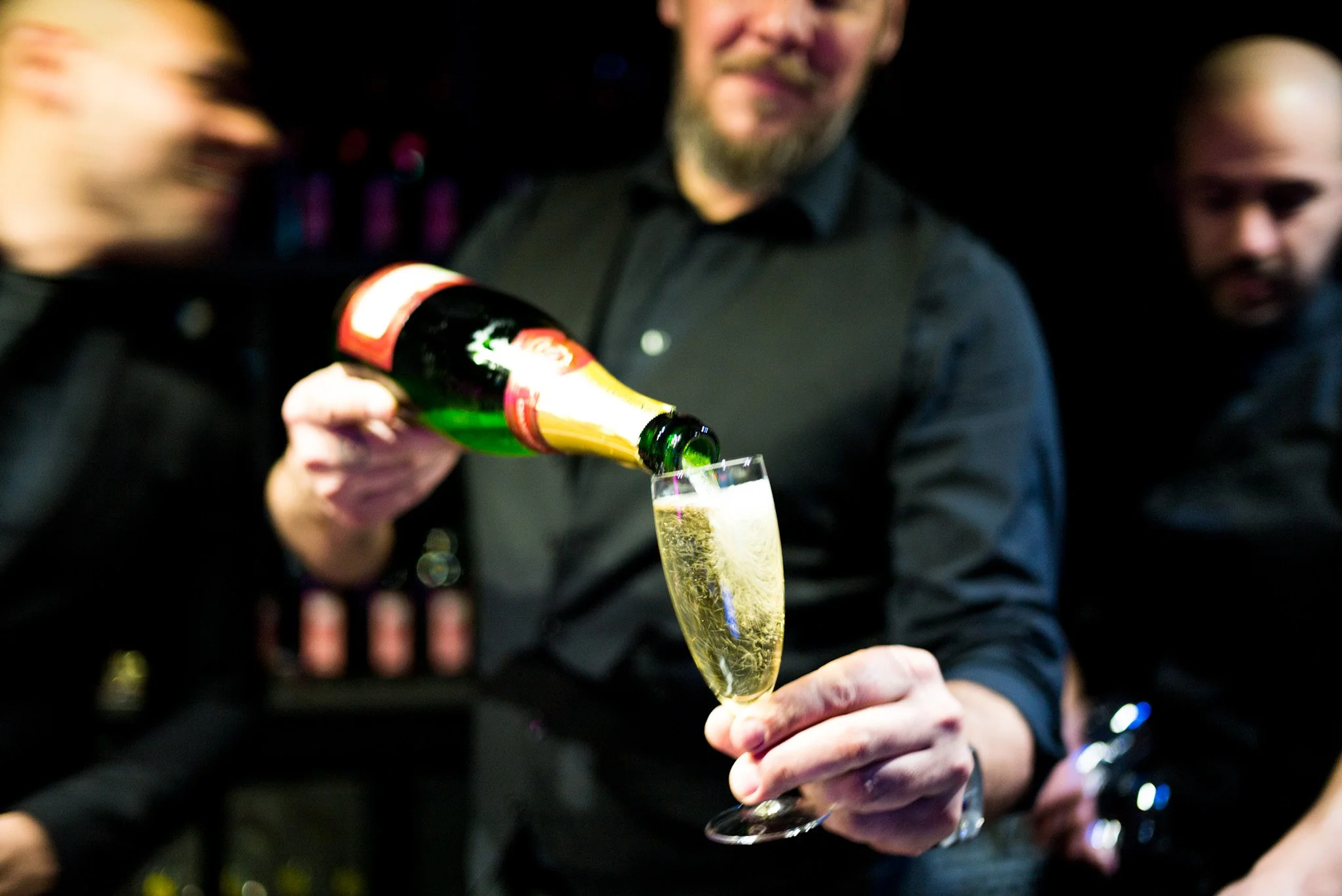 Un serveur verse du champagne dans une flûte lors de la soirée annuelle Régus à Paris. Ambiance festive et élégante avec des lumières tamisées, capturant l'esprit de célébration et de networking professionnel.