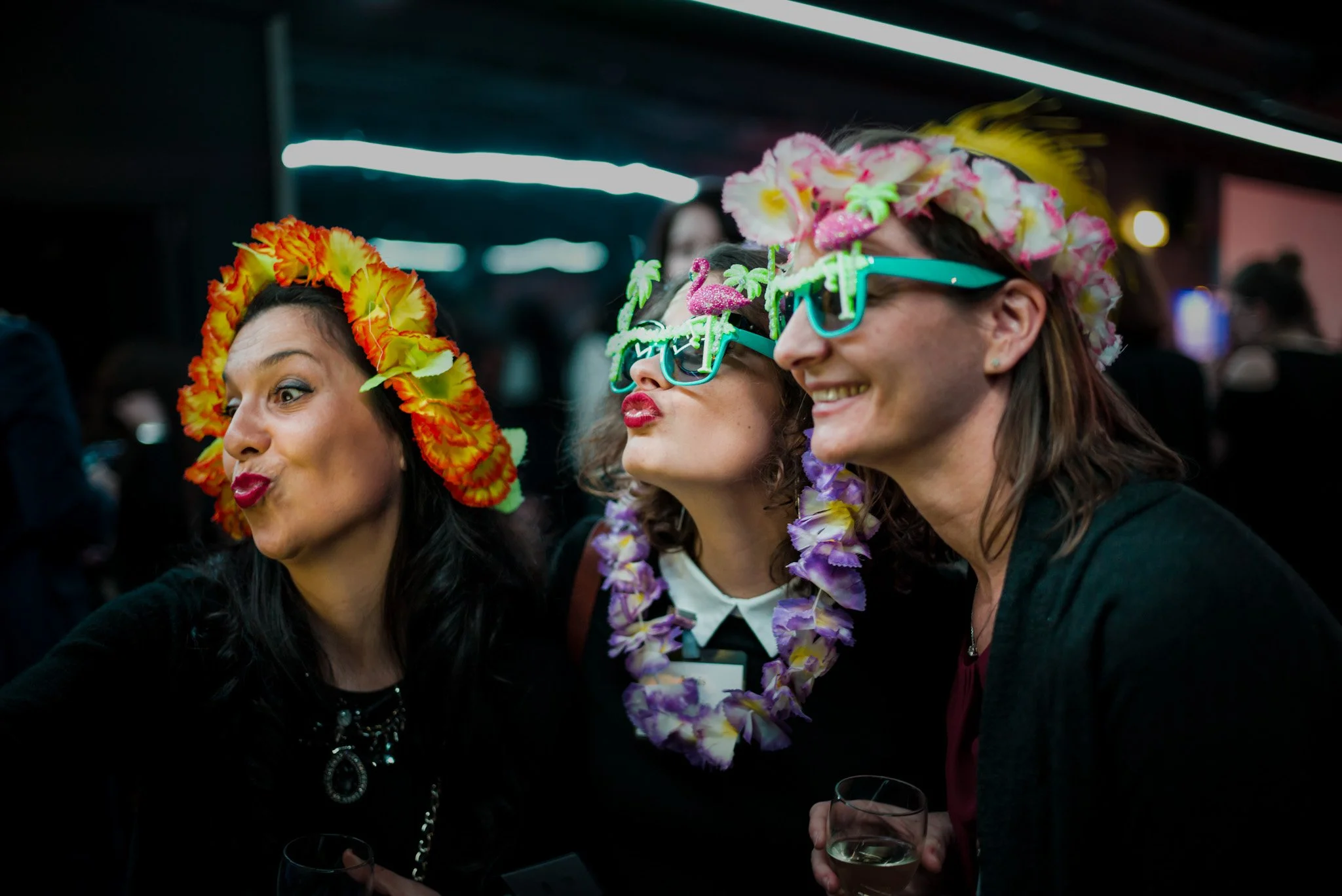 Trois femmes en accessoires festifs (couronnes, lunettes) lors de la soirée Régus. Ambiance ludique et colorée, montrant la dimension festive et décontractée de l'événement professionnel.