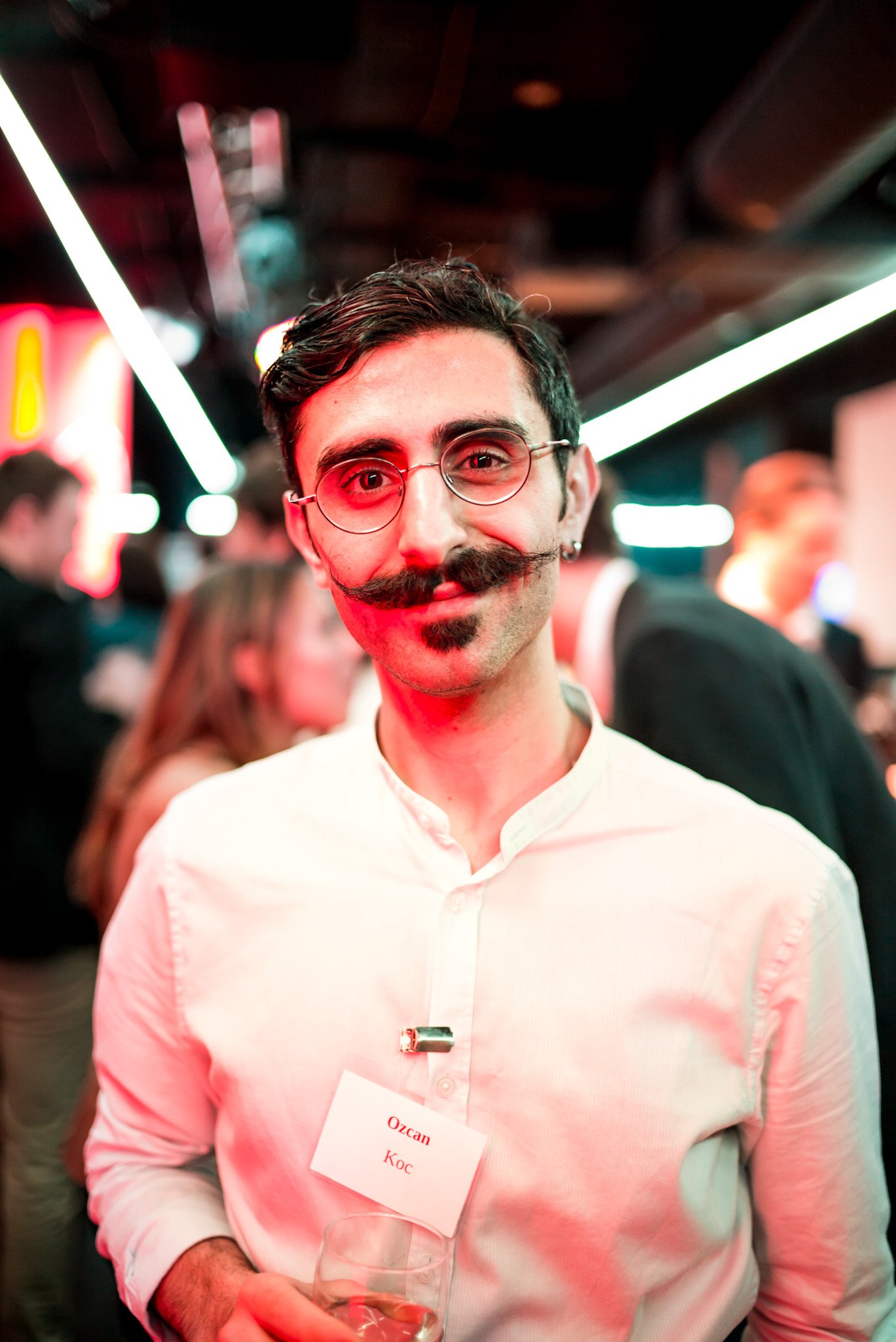 Ozcan Koc sourit à l'objectif pendant la soirée Régus à Paris. Badge visible, ambiance lumineuse et dynamique, représentant les participants engagés et conviviaux de cet événement professionnel.