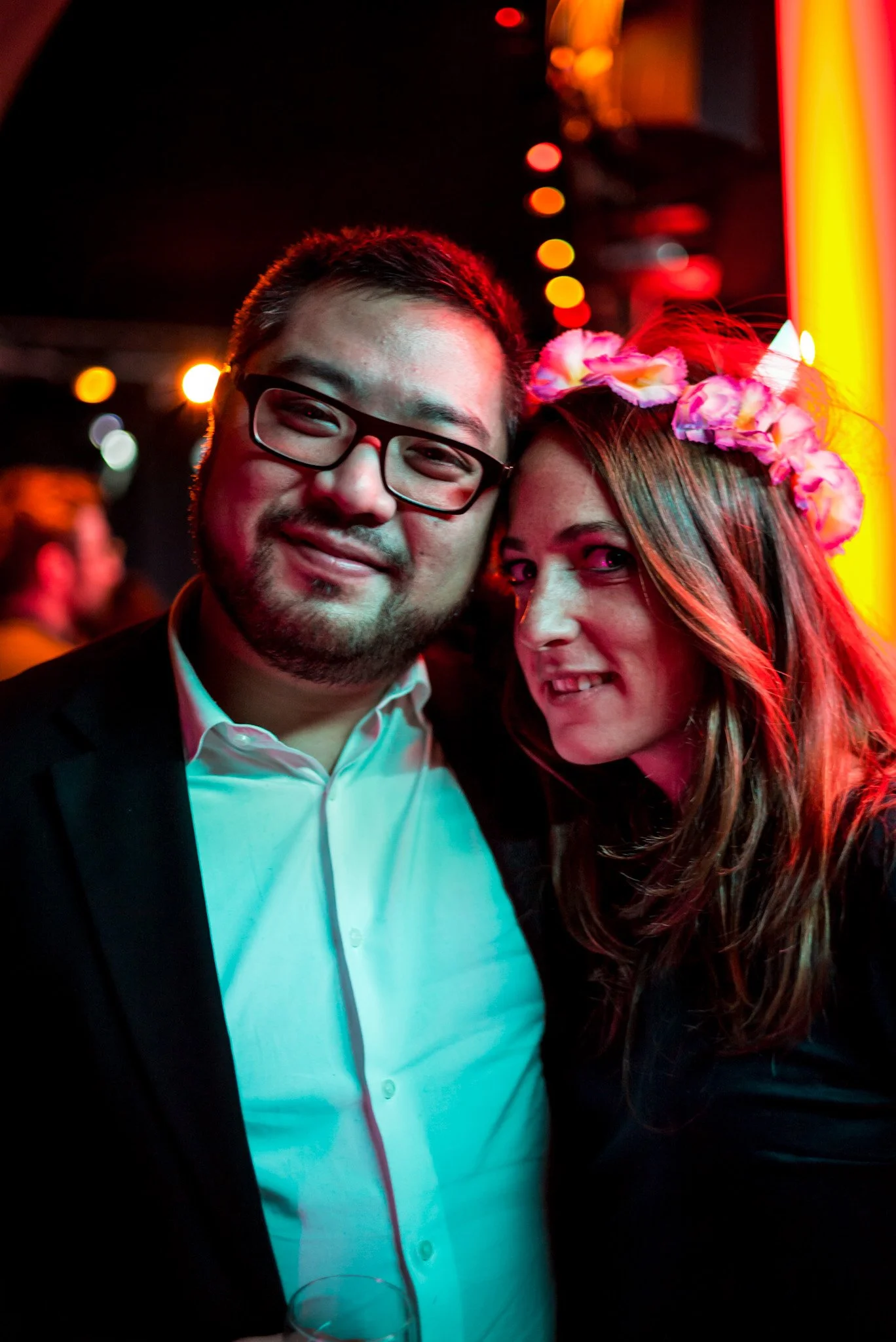 Un homme et une femme posent avec des accessoires floraux lors de la soirée Régus Paris. Ambiance romantique et festive, éclairage chaud, illustrant les moments de complicité et de célébration de la soirée.