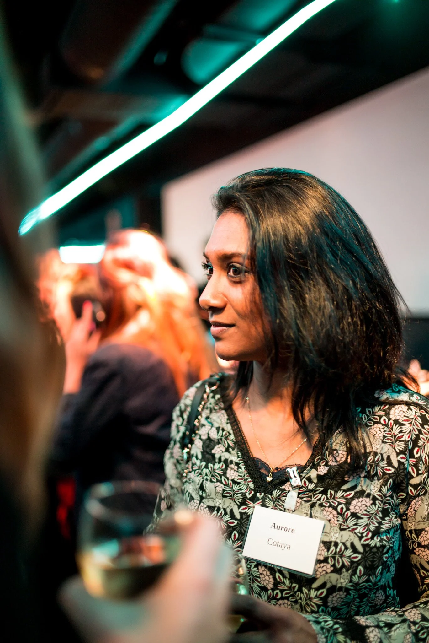 Aurore Cotaya en conversation lors de la soirée Régus Paris. Badge visible, ambiance lumineuse et moderne, illustrant les échanges professionnels et les connexions
