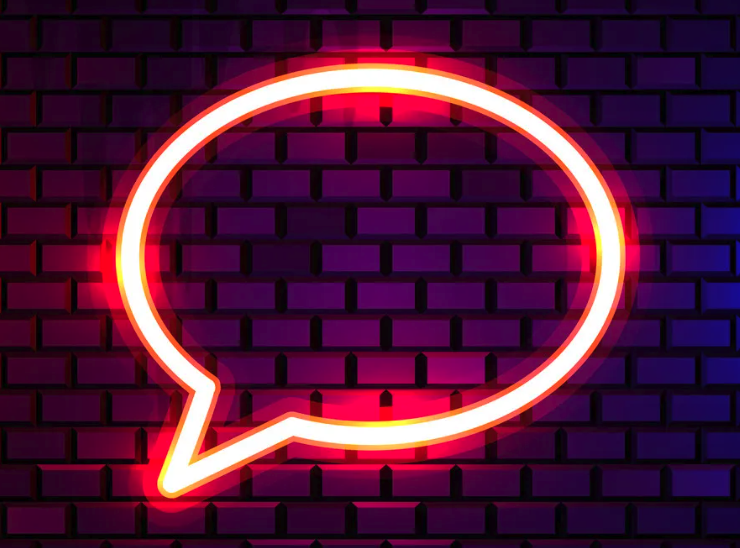 Neon sign in the shape of a speech bubble on a brick wall background