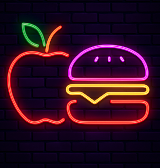 Neon sign of a stylized apple and hamburger burger on a dark brick wall background.