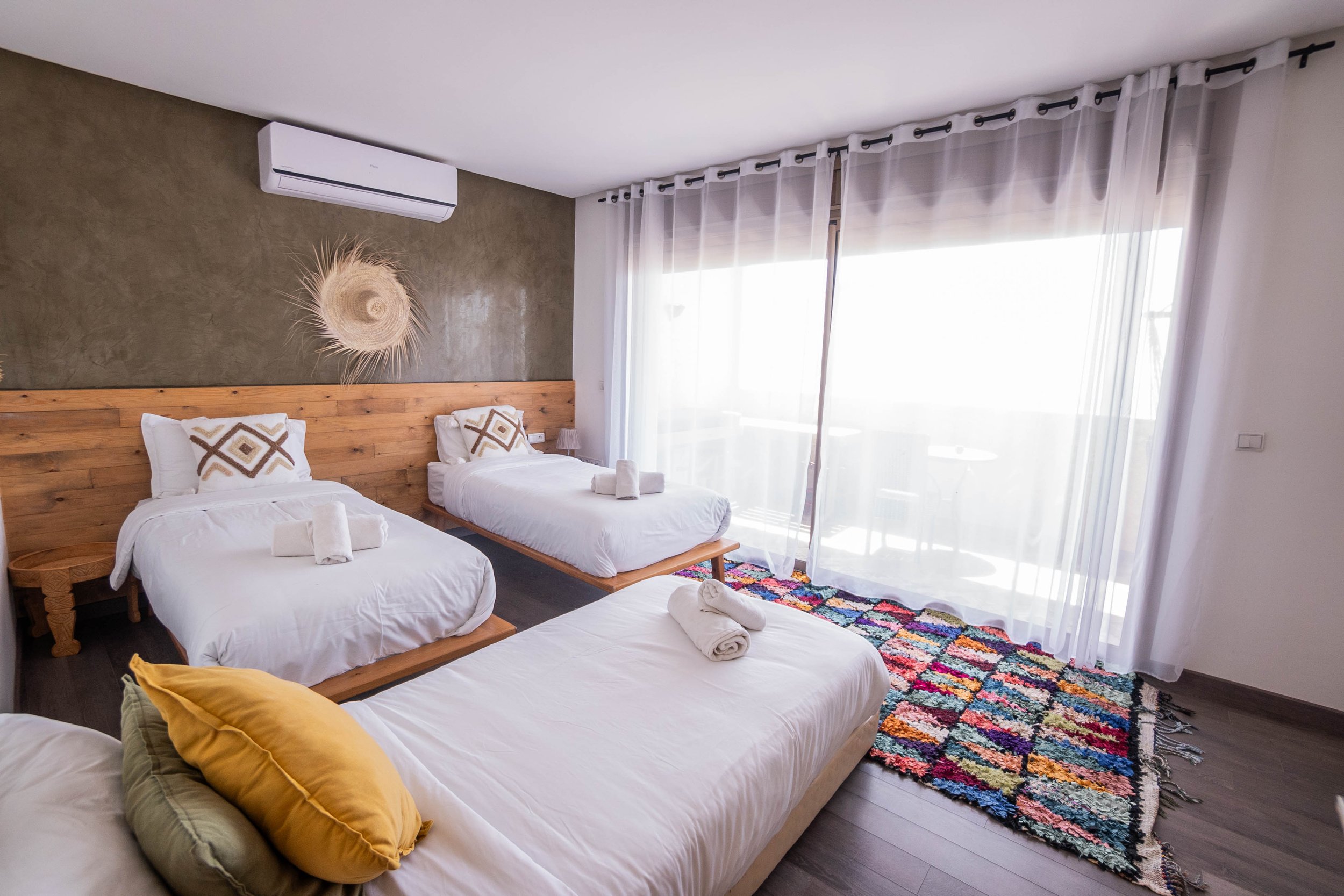 Deluxe triple room with sea view and colorful rug at our surf camp in Tamraght