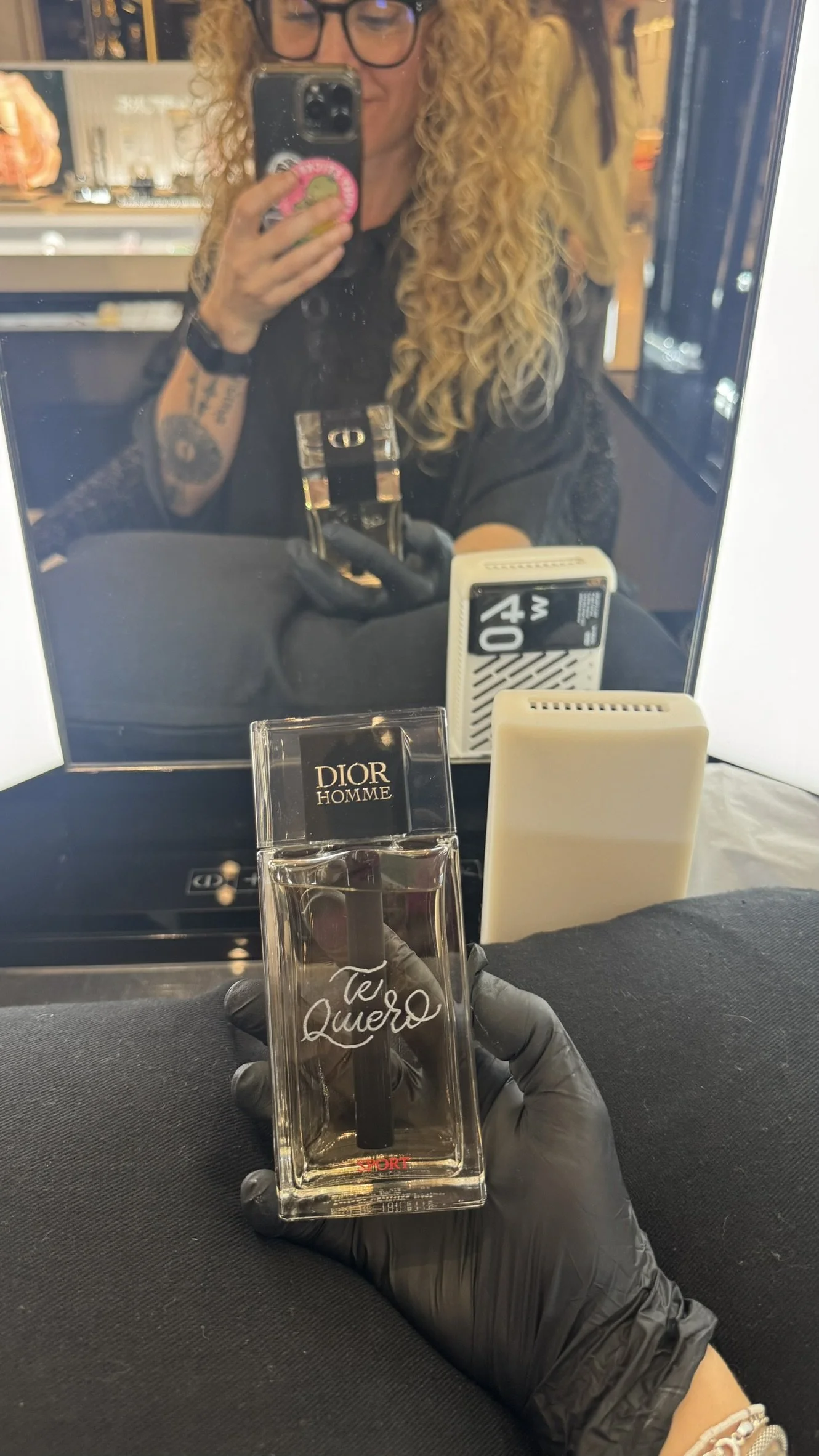 Fundadora de Bendita Caligrafía con guantes negros sostiene un frasco de perfume con la frase "Te Quiero" grabada con torno para Dior.