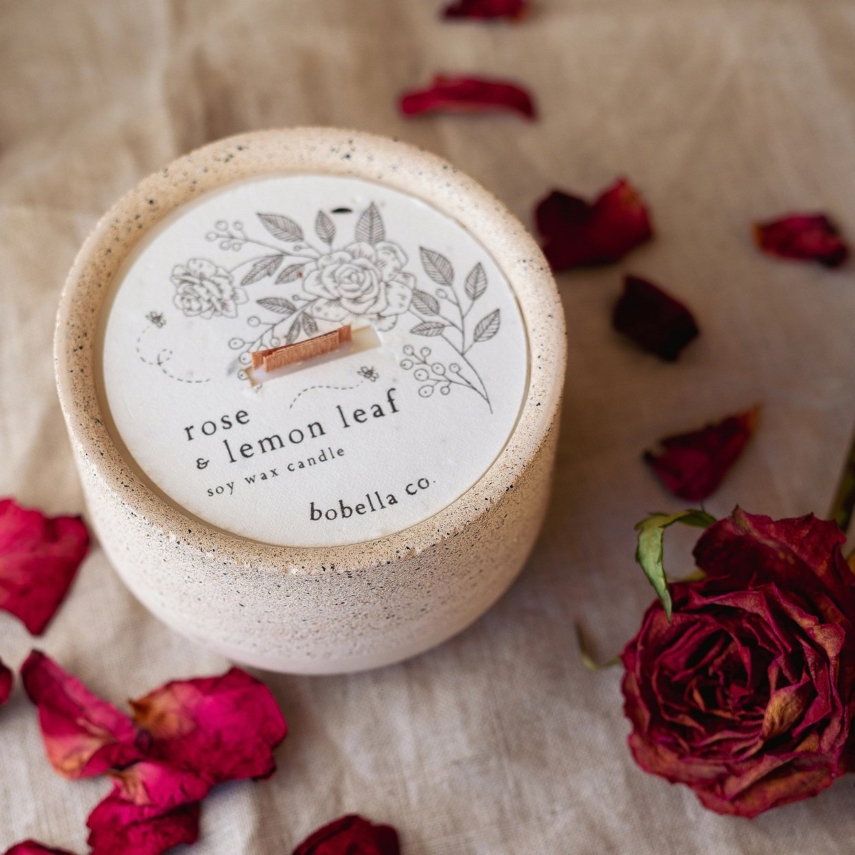 Hand-poured Rose & Lemon Leaf soy wax candle in a hand-cast speckled stoneware vessel with a plantable wildflower dust cover.