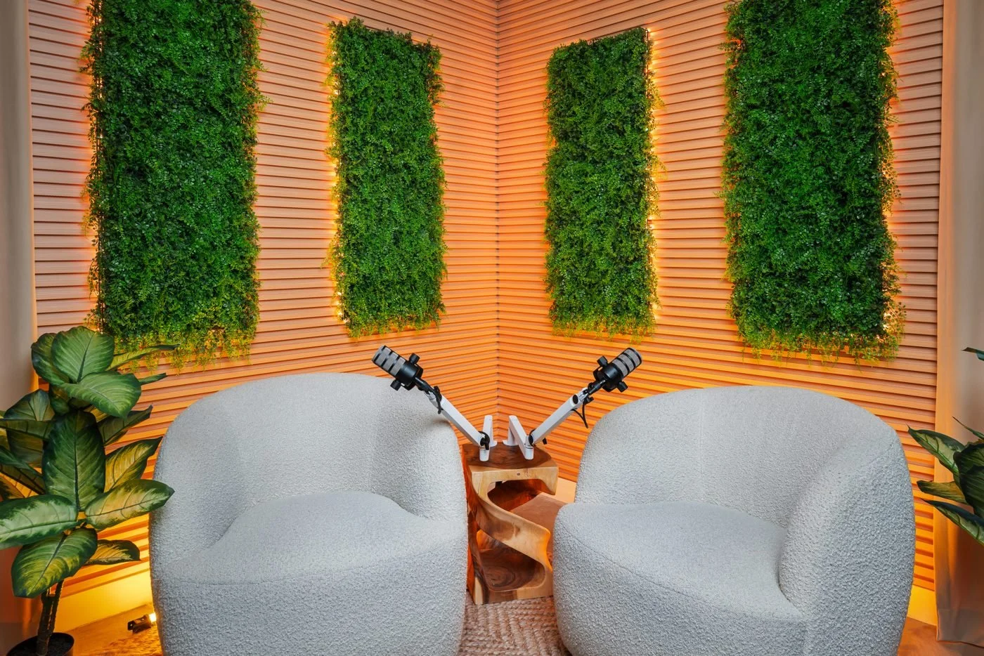 Greenery backdrop with white chairs and microphones for a relaxed conversation setup.