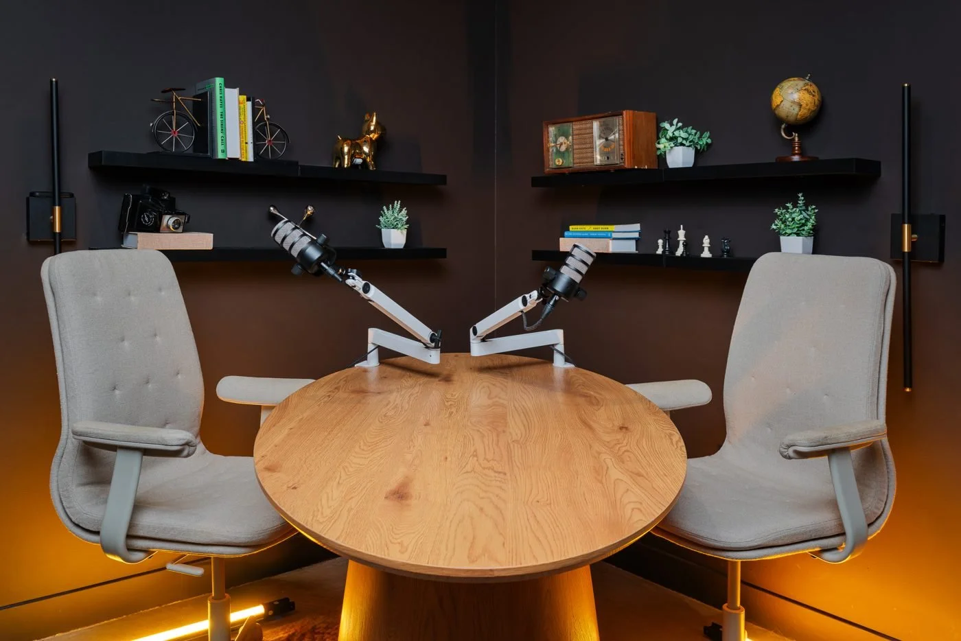 Office backdrop with an oval table, chairs and microphones for podcast recording.
