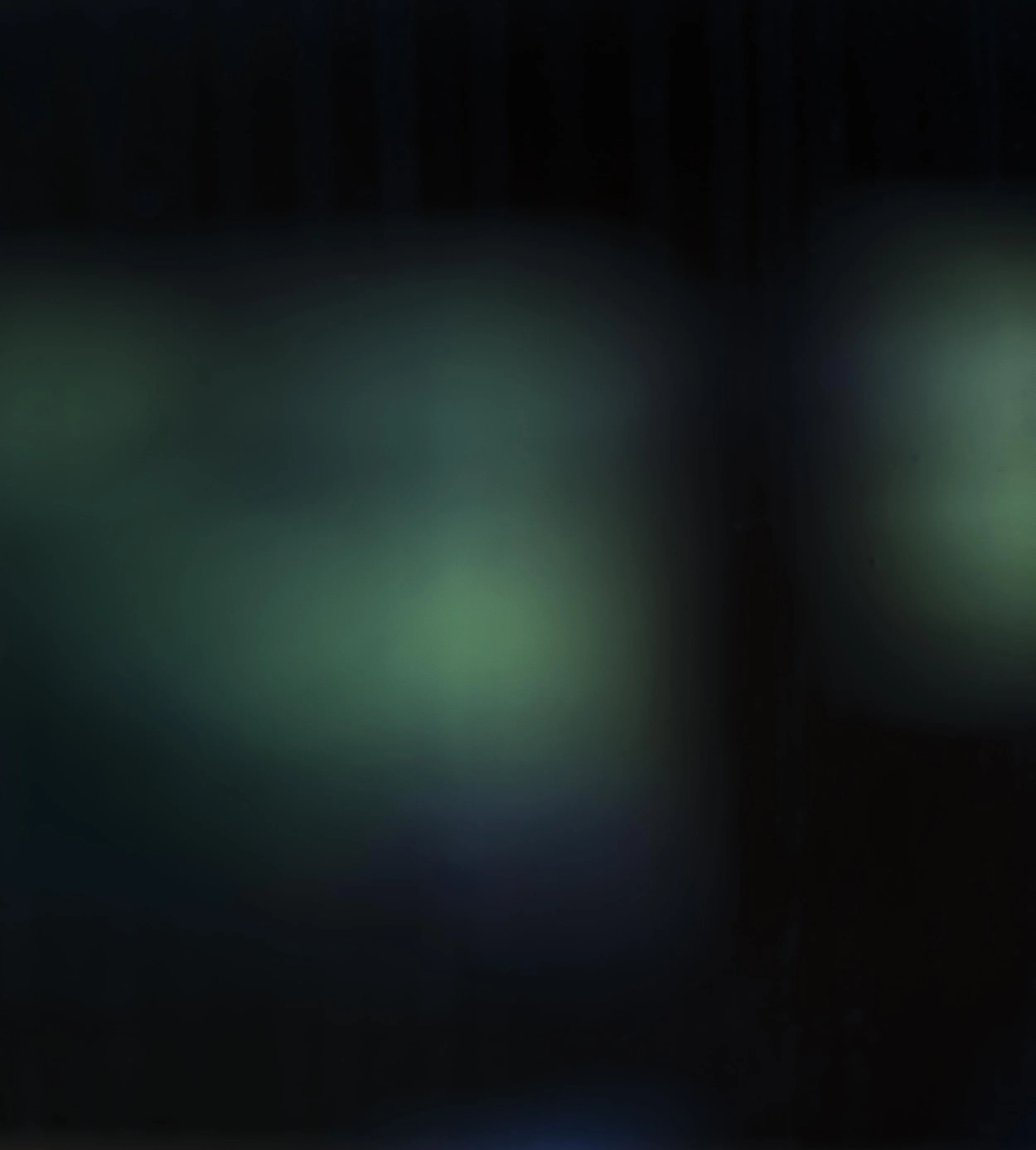 Blurred abstract image with green and black color gradients and bokeh light effects.