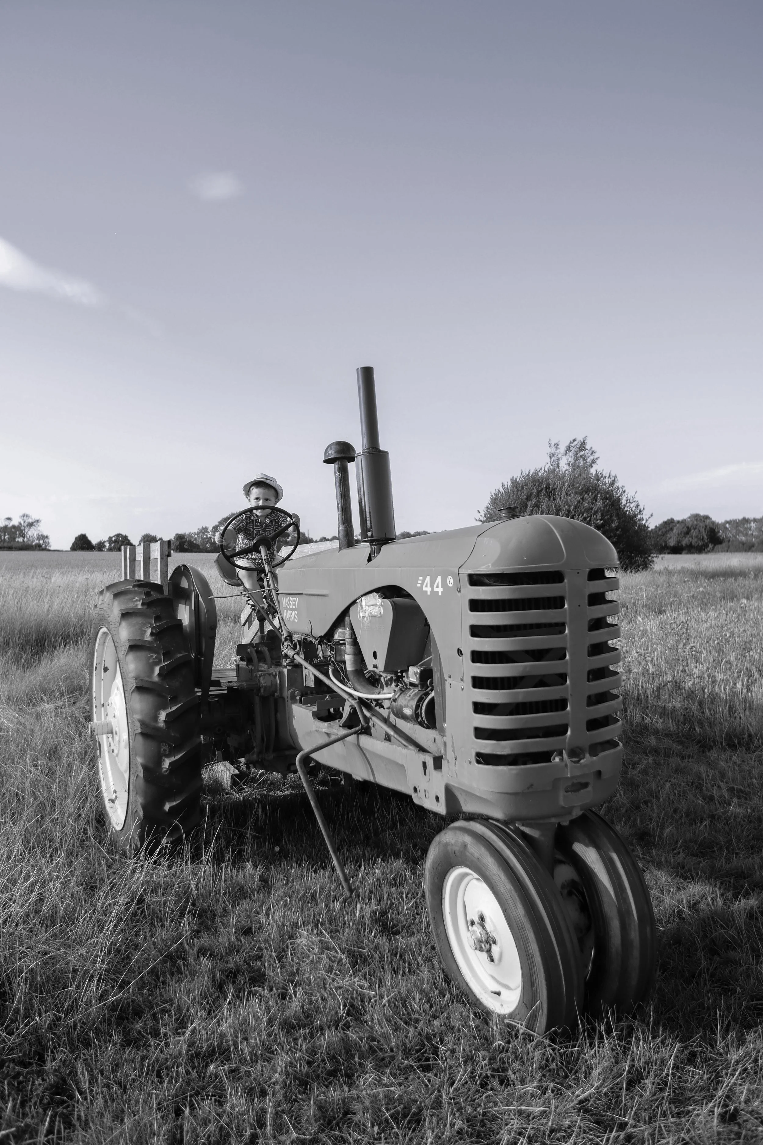 A child riding a vintage tractor in a field.