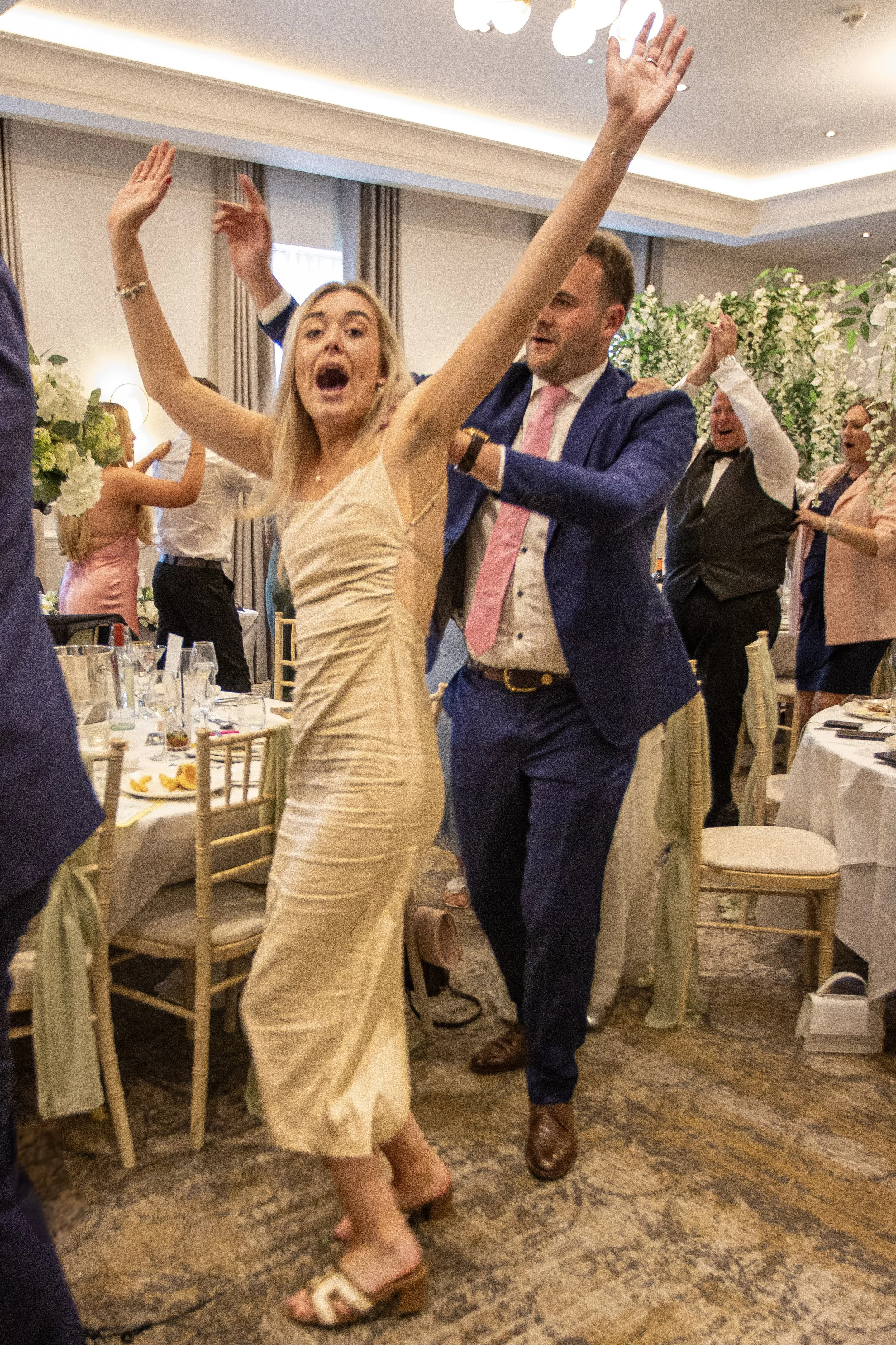 People dancing and celebrating at a wedding reception in a decorated banquet hall.
