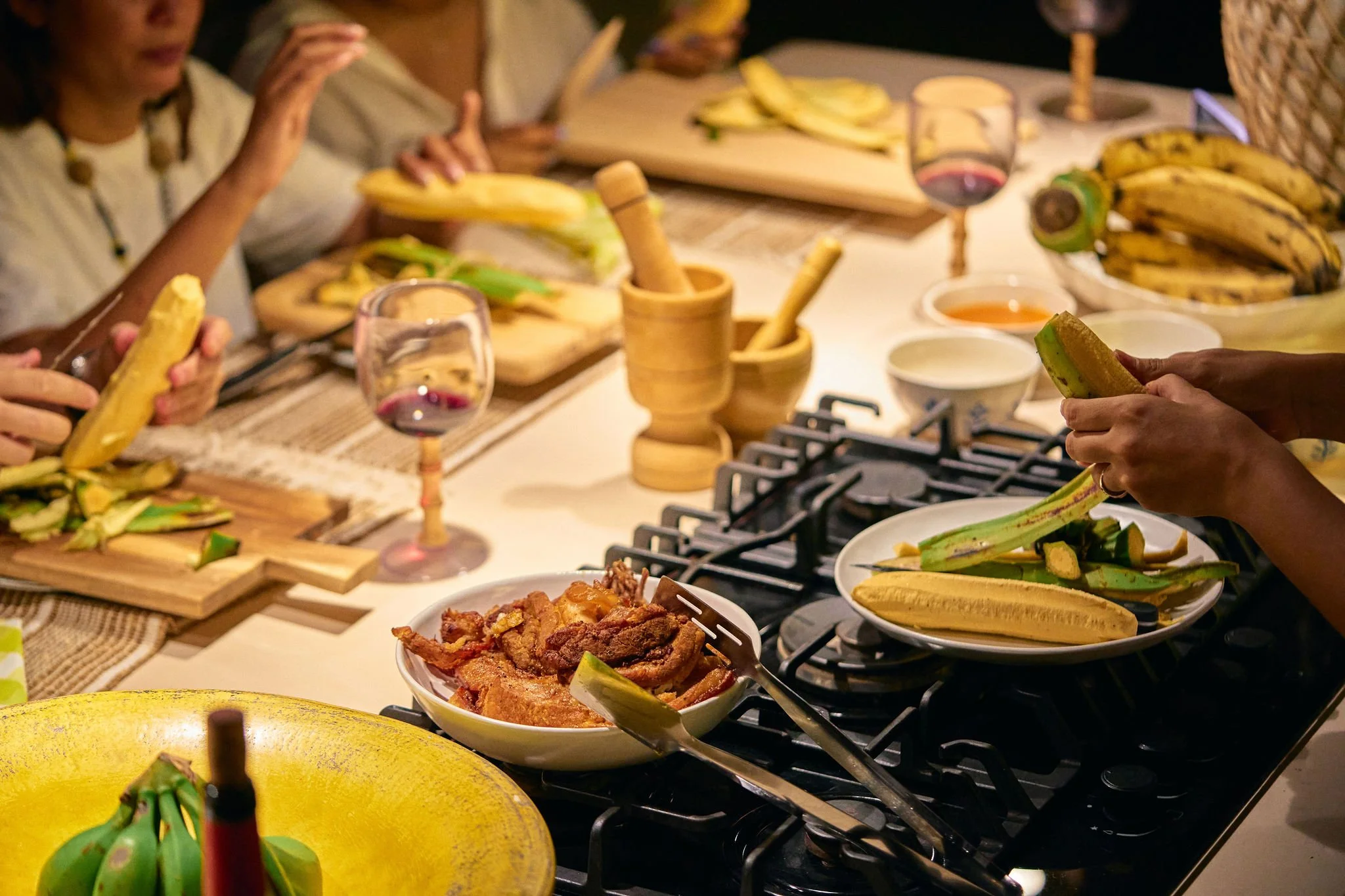 Personas sirviendo plátanos maduros y preparando comida en una mesa con bebidas y platos