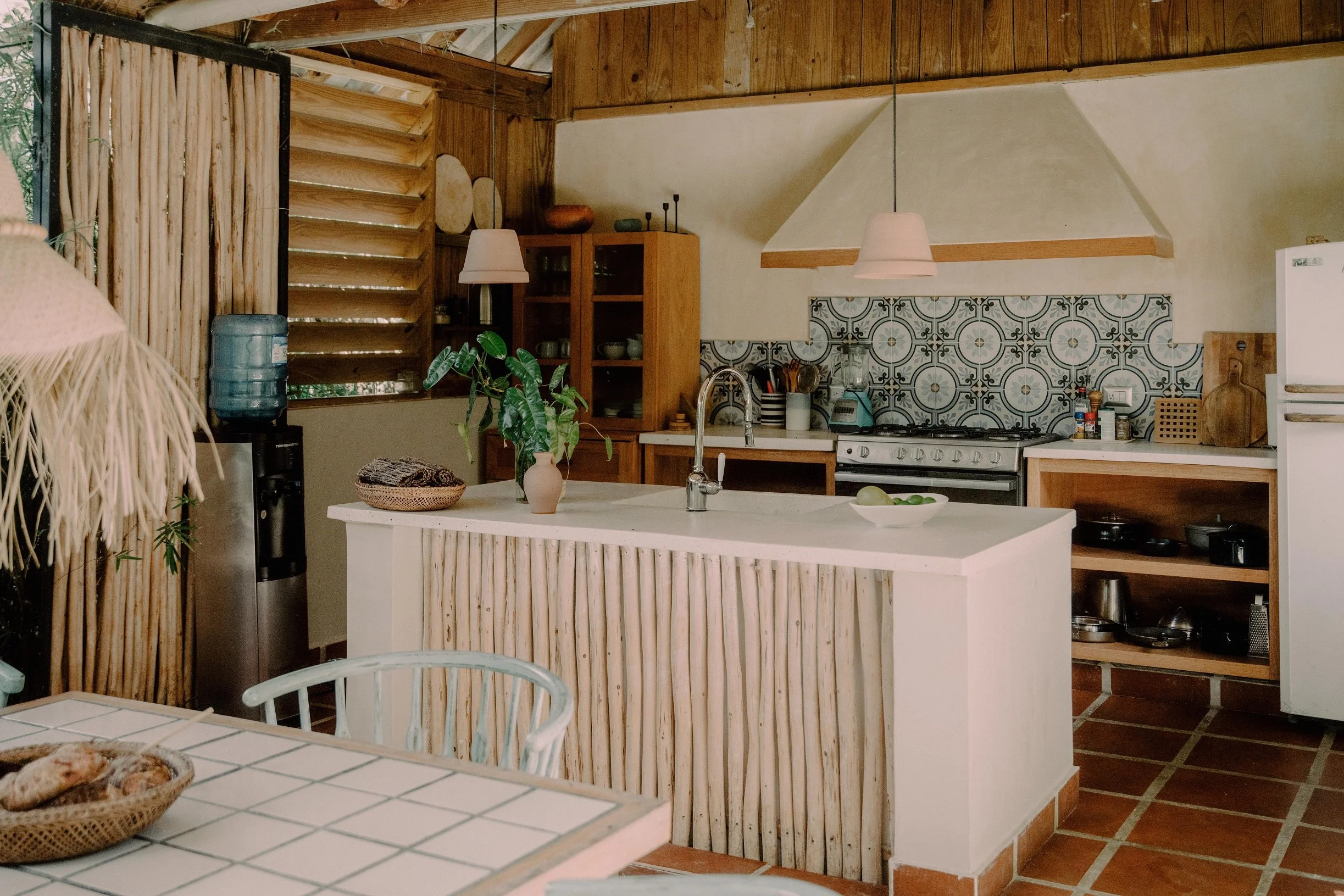 Cocina rústica con encimera de piedra, gabinetes de madera y paredes con azulejos decorativos, estilo campestre.