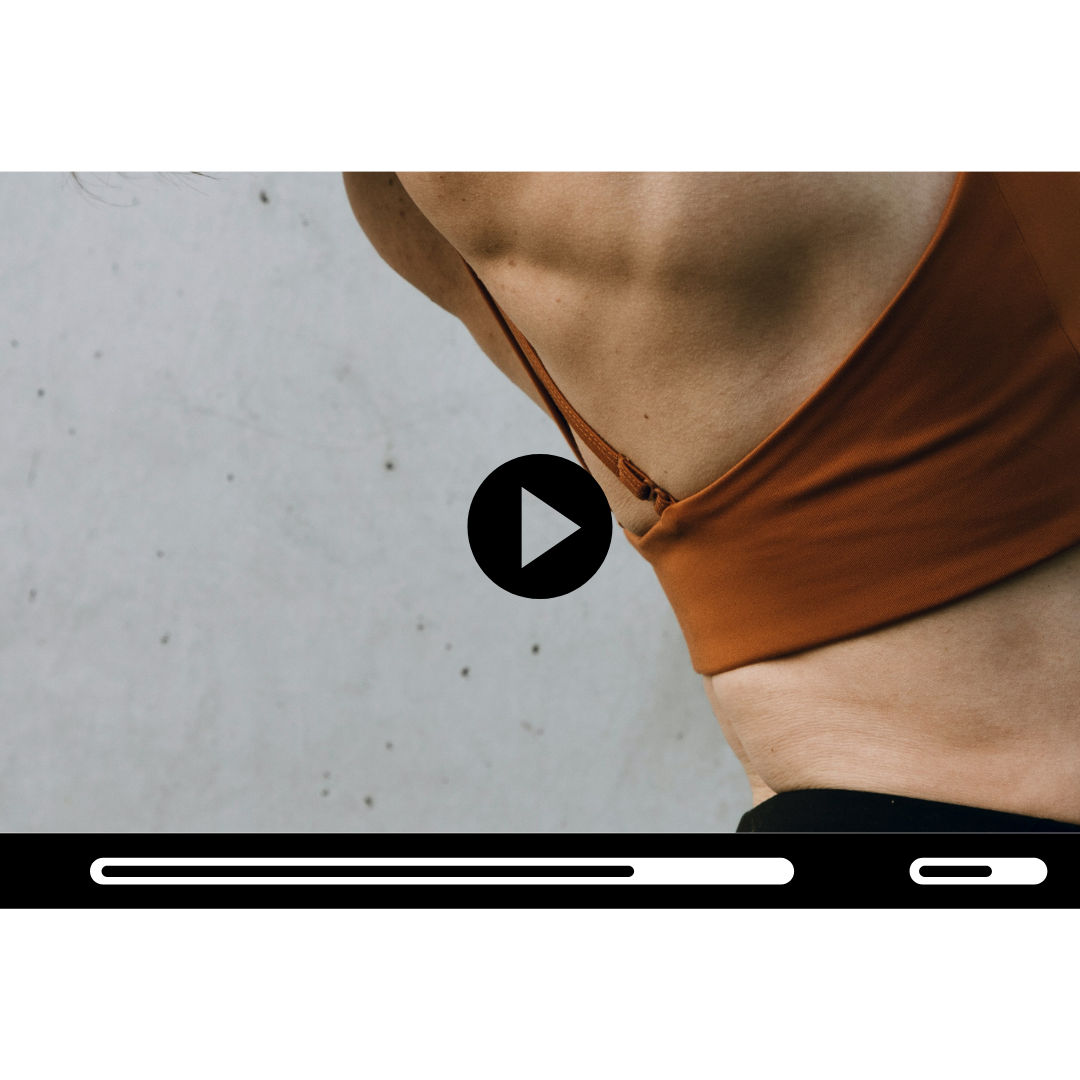 Close-up of a woman's midsection, wearing a brown sports bra, against a gray concrete wall background.