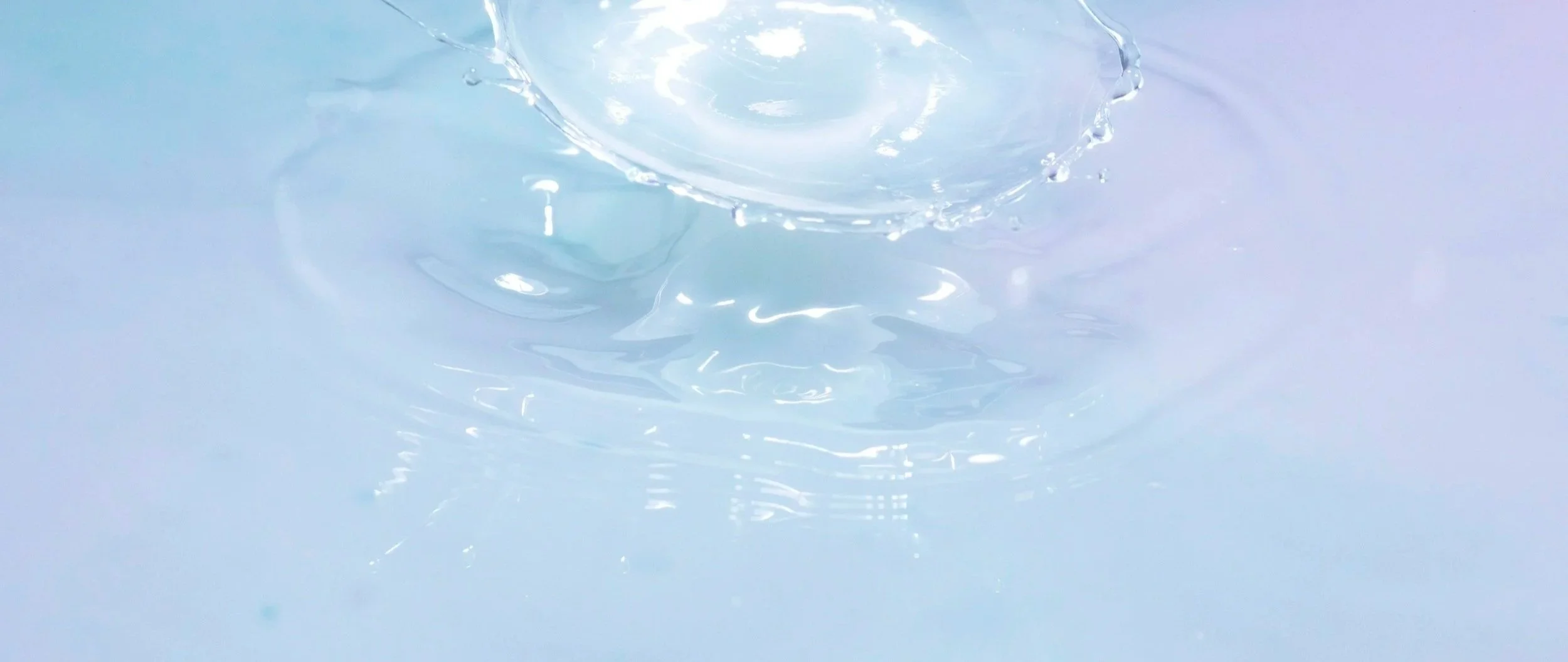 Close-up of a splash in clear water creating ripples and droplets.
