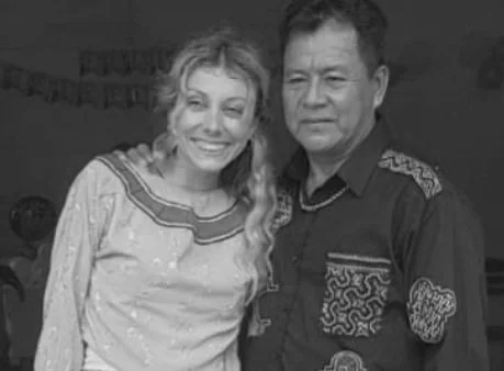 A smiling woman with curly hair and a man in a patterned shirt standing together.