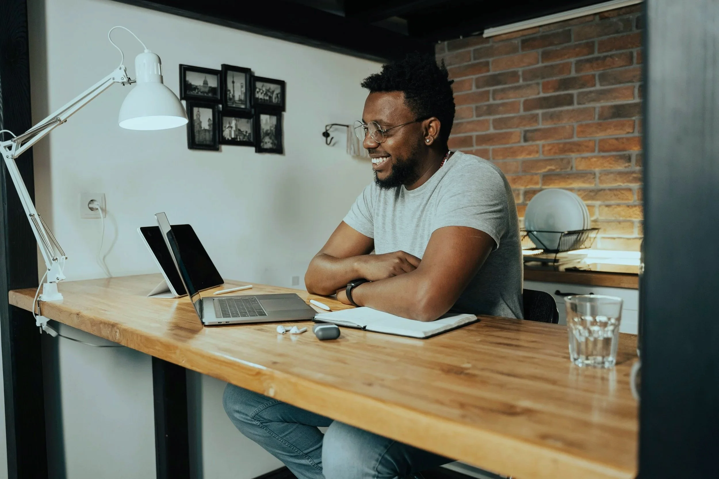 A man sitting at a wooden desk, smiling while looking at rental property owner statement on a laptop.