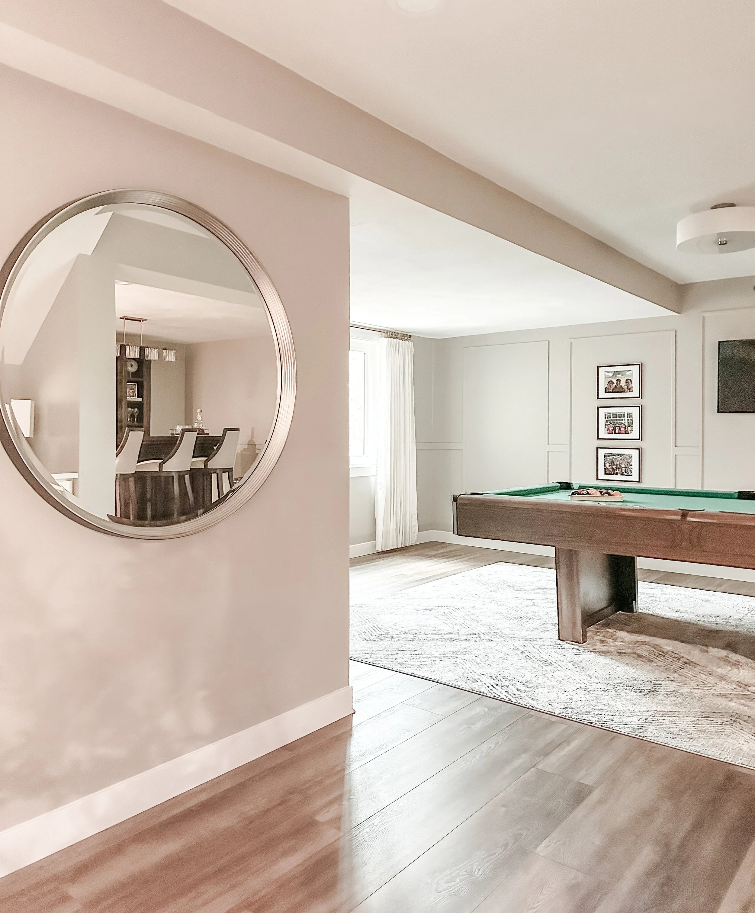 Living room with pool table, wall art, window with curtains, and a large mirror on the wall.