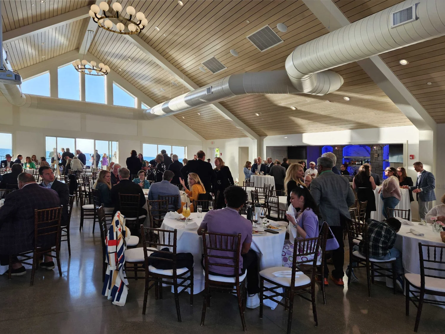 Event hall inside the Sunset Pavilion with a vaulted wood ceiling, chandeliers and guests seated at round tables