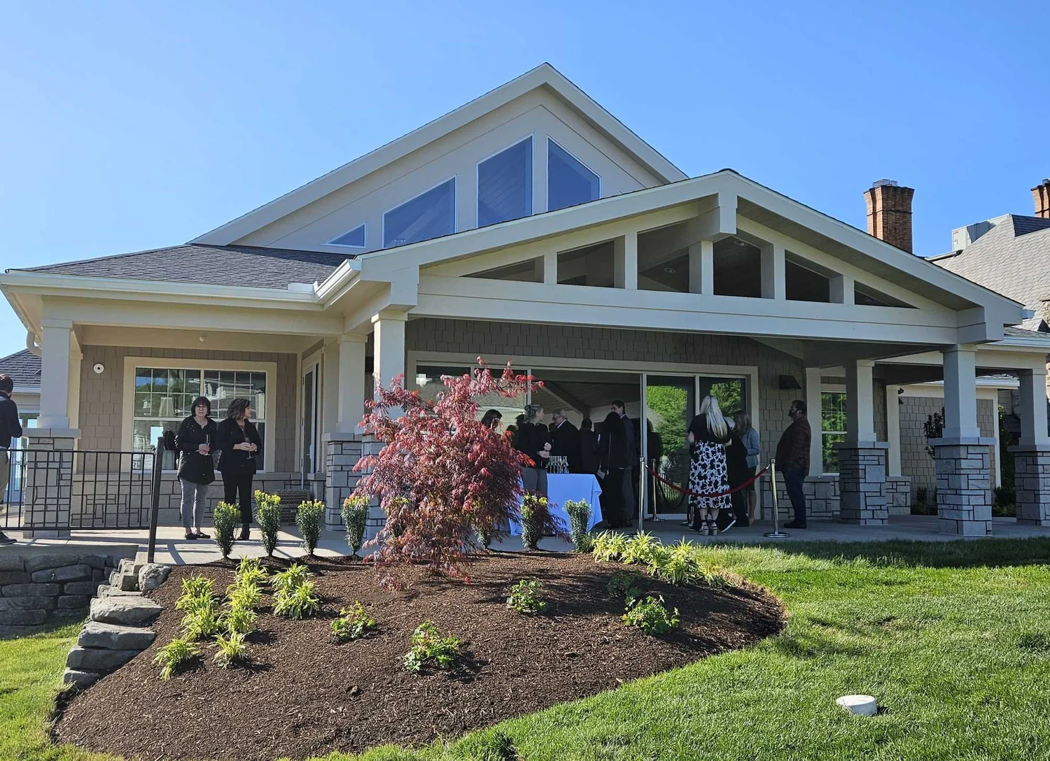 Rear terrace of the Sunset Pavilion with a glazed gable, stone column bases and guests gathering outside