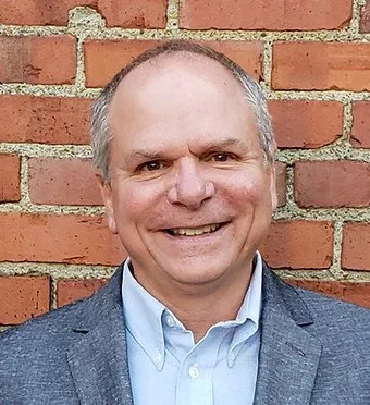 Portrait of Joe Myers in front of a brick wall