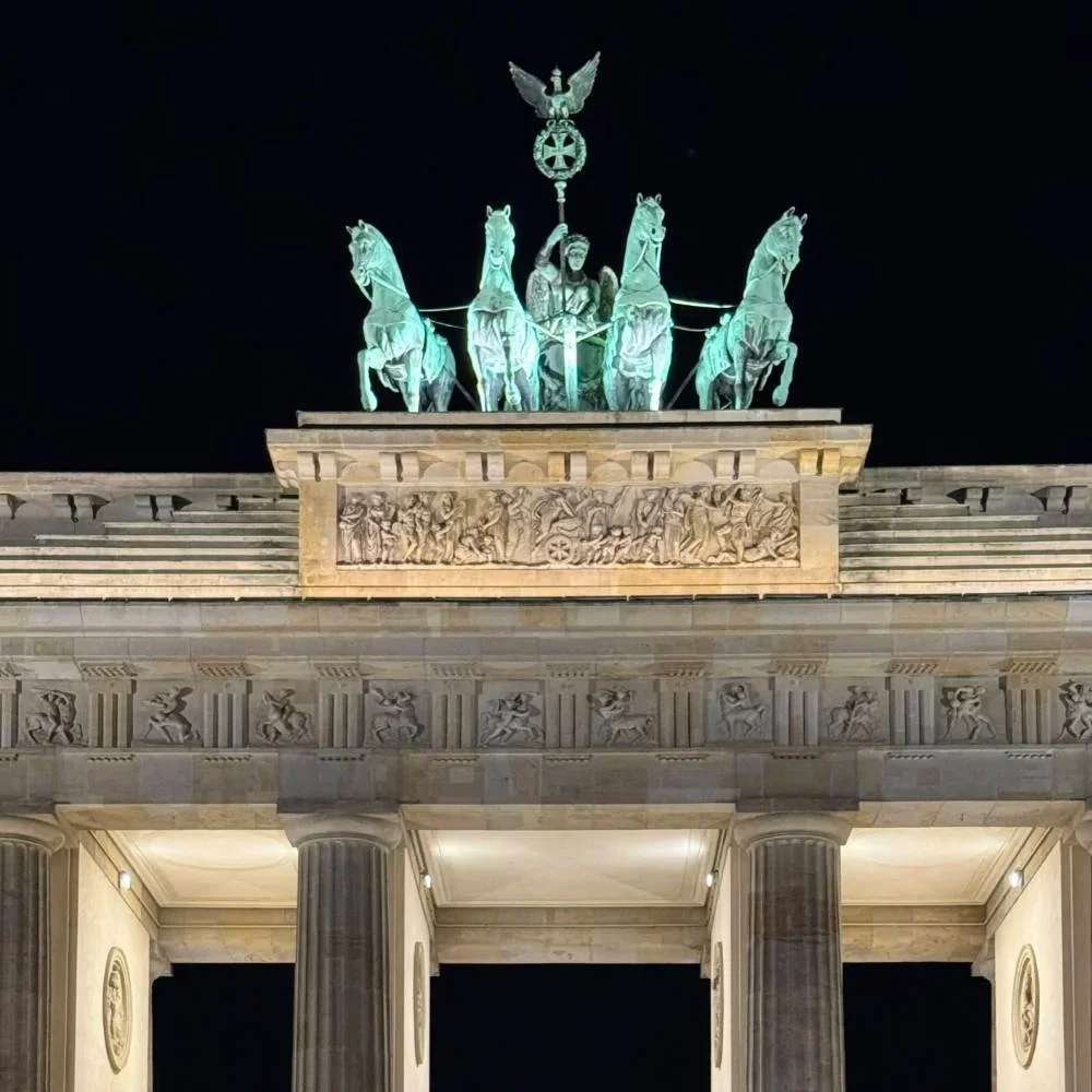 The Quadriga statue — four horses pulling a chariot — atop the Brandenburg Gate in Berlin, lit at night