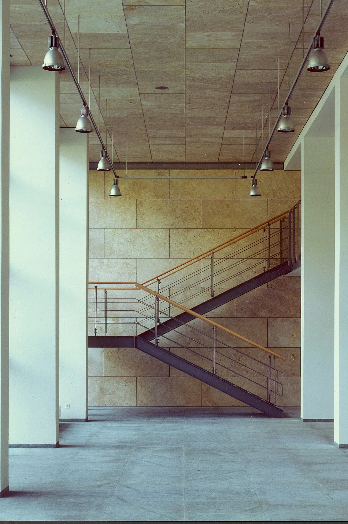 Hall with a steel stair against a stone wall