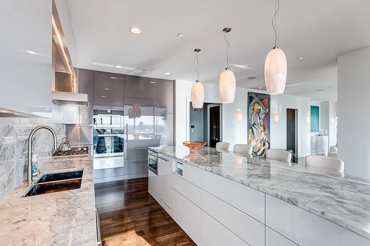 Bright modern kitchen with pendant lights over a long marble island