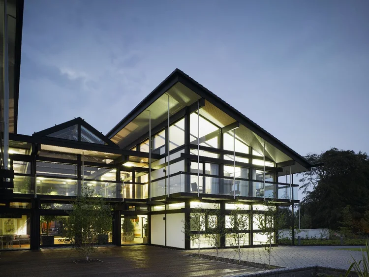 Night view of a tall glazed gable with balconies and lit rooms on every floor