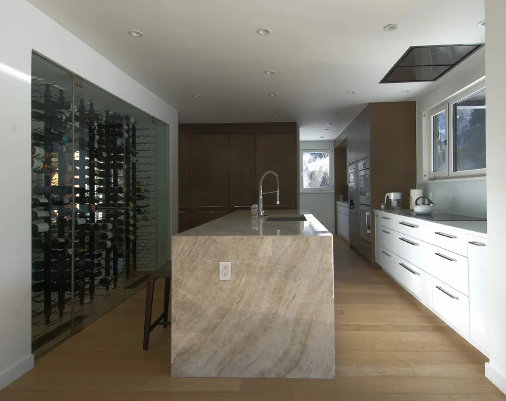 Kitchen island in front of a glass wine wall