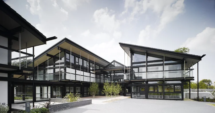 Courtyard between the buildings, with black timber frames, full-height glass and a paved outdoor space