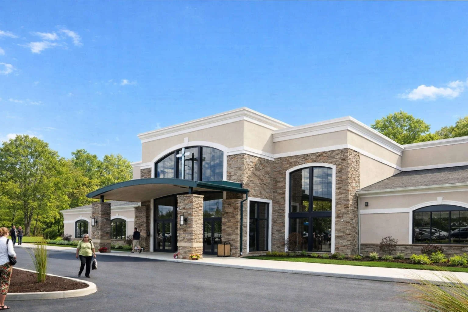 Modern commercial building with stone and stucco exterior, large glass windows, and a curved entrance canopy, surrounded by a paved parking lot and landscaping, under a blue sky.