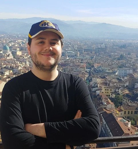 Portrait of Ryan Schmidt with a city and mountains behind him