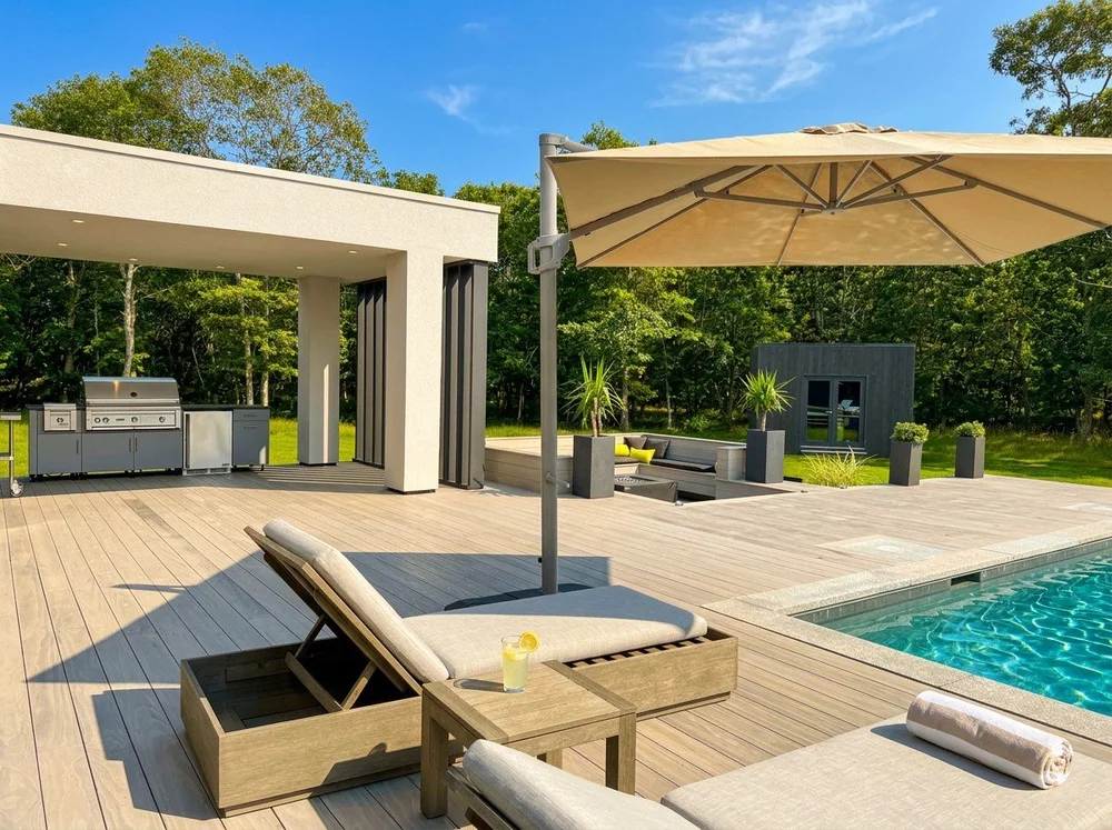 Pool deck with a covered outdoor kitchen, loungers and a large umbrella