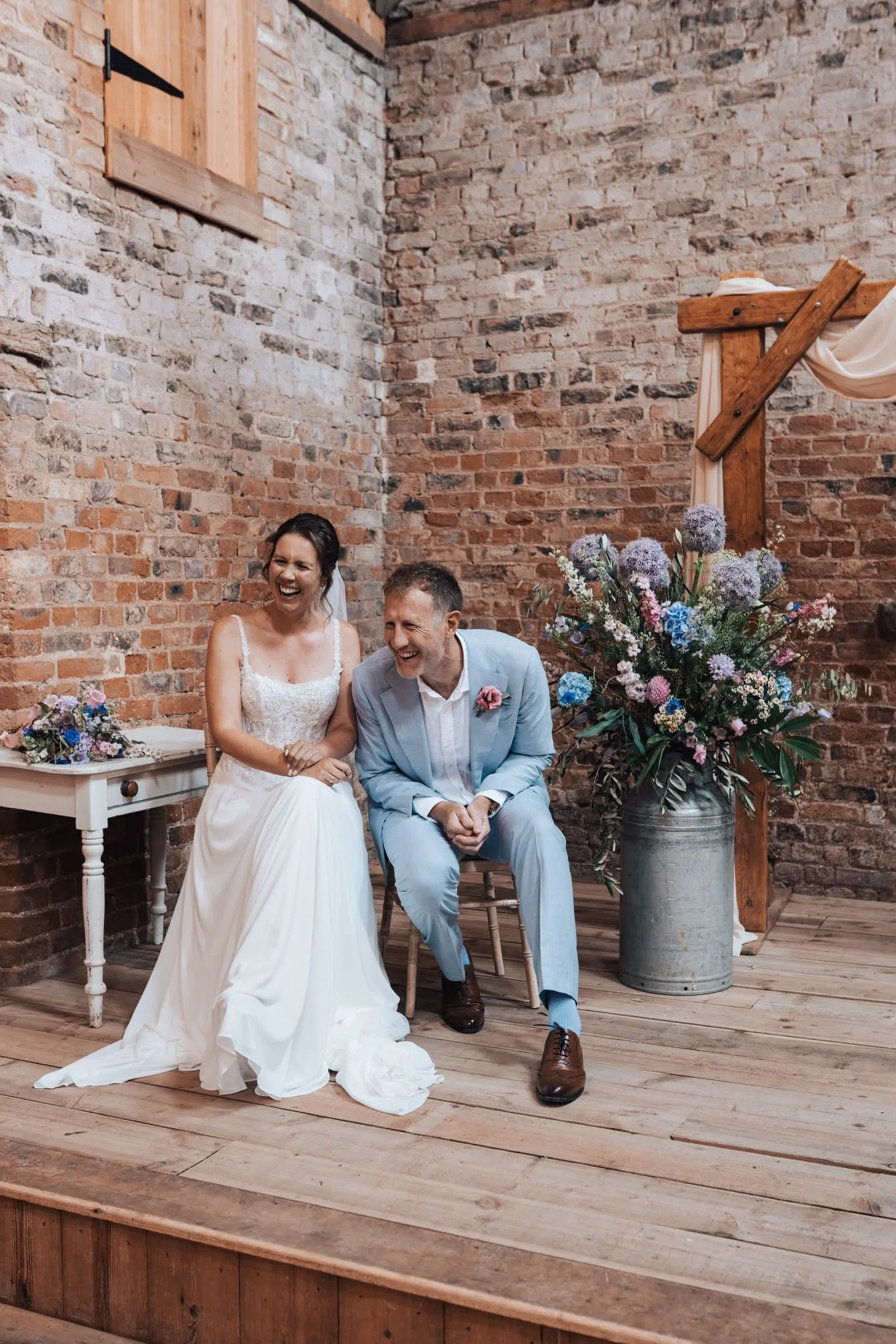 Couple laughing during independent wedding celebrant-led wedding ceremony by Surrey Wedding Celebrant at Milton End Barns, The Cotswolds. Photo: Paul Cuthbertson