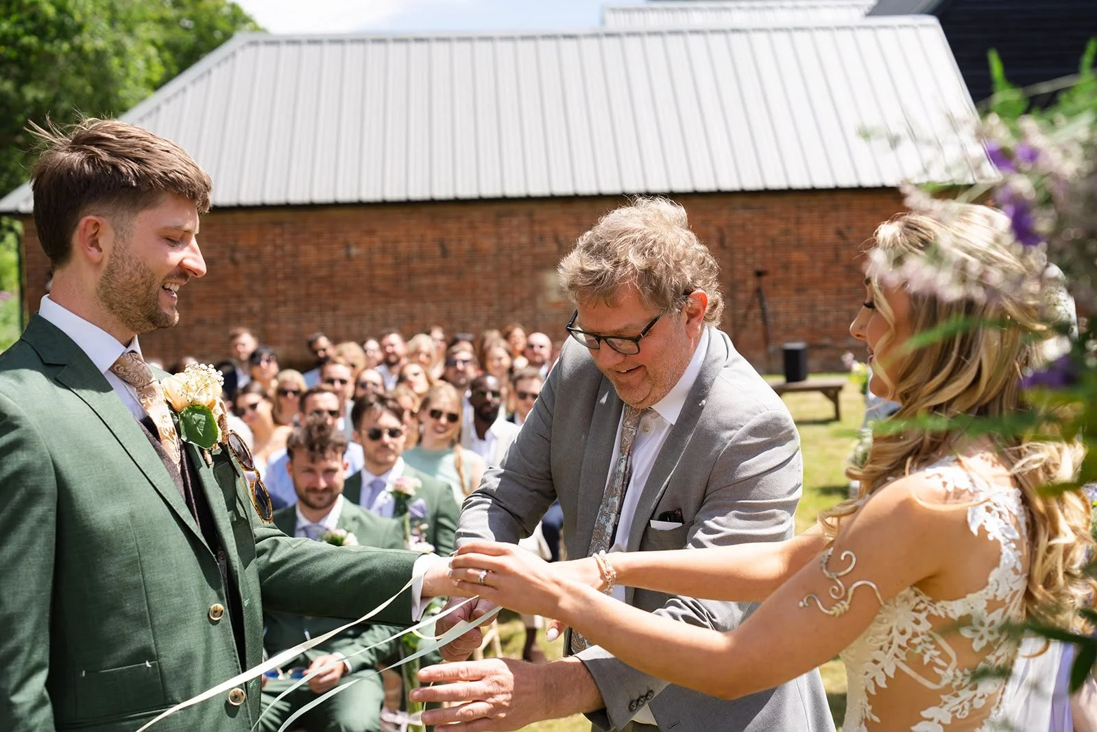 Parent lays ribbon as part of handfasting ritual within a personal wedding ceremony led by an independent wedding celebrant creating and delivering wedding ceremonies in Surrey and South East England. Photo: Soulful Reflection