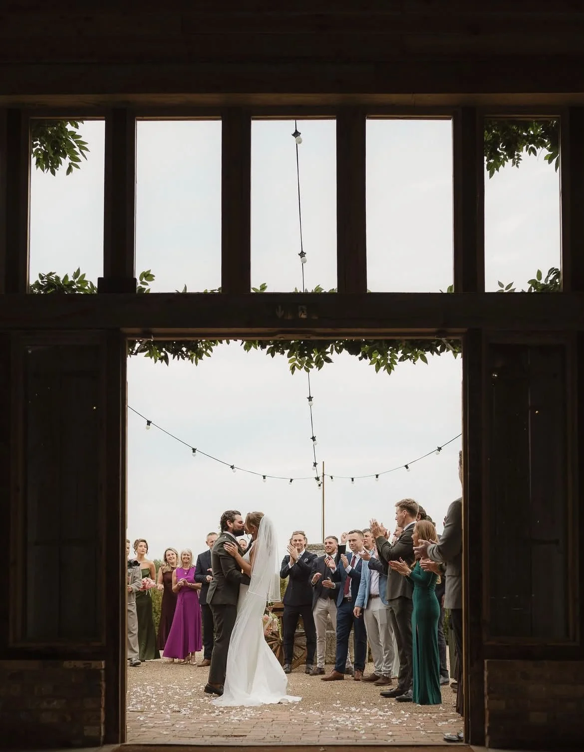 Bride and groom kiss to celebrate their heartfelt and relaxed  wedding ceremony at High Billinghurst Farm, led by an independent Surrey wedding celebrant. Photo: Leanne Peacock Photography